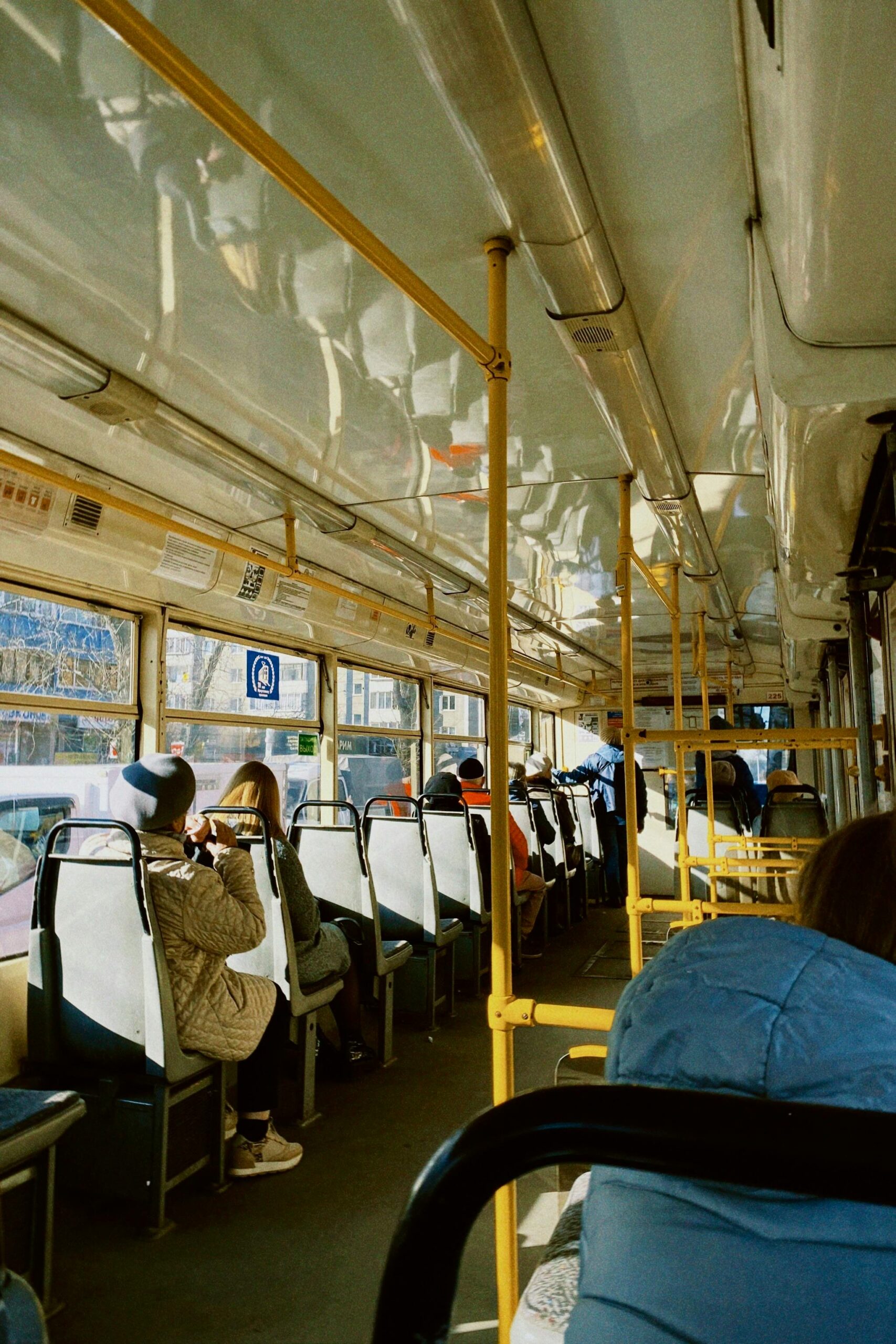 People seated on a sunlit bus, showcasing daily commuting life in urban public transport.