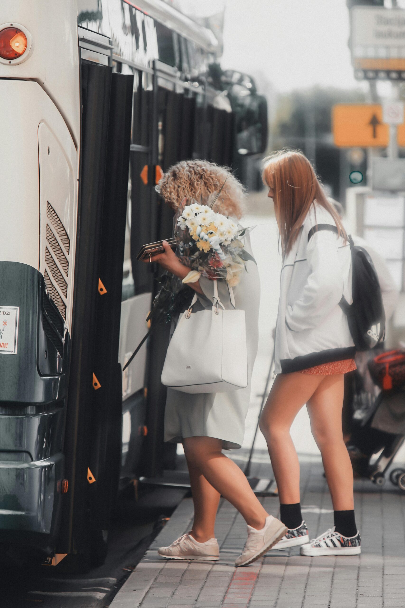 Two women boarding a city bus in Riga, Latvia, showcasing daily urban life.
